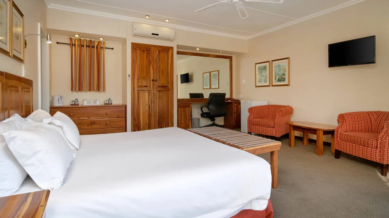 Hotel room with a large bed two armchairs desk and wallmounted TV