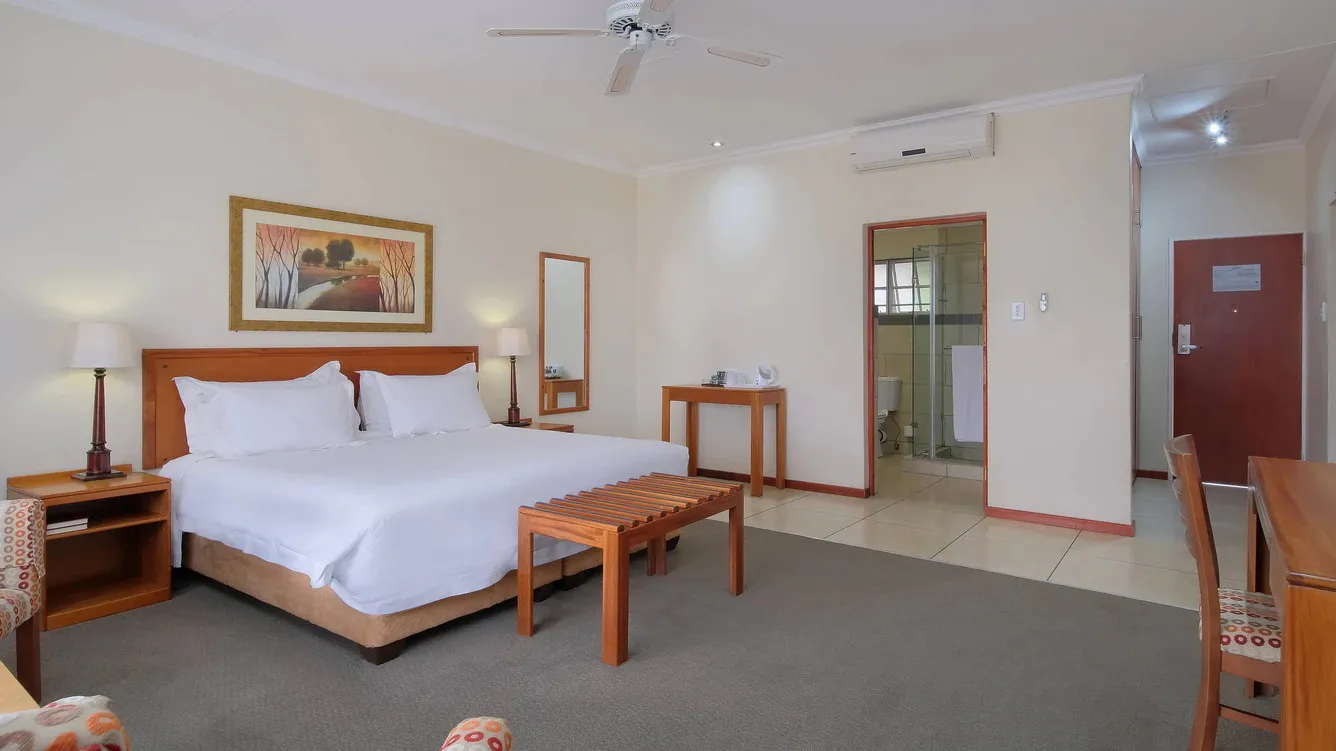 Hotel room with a large bed wooden furniture and an ensuite bathroom