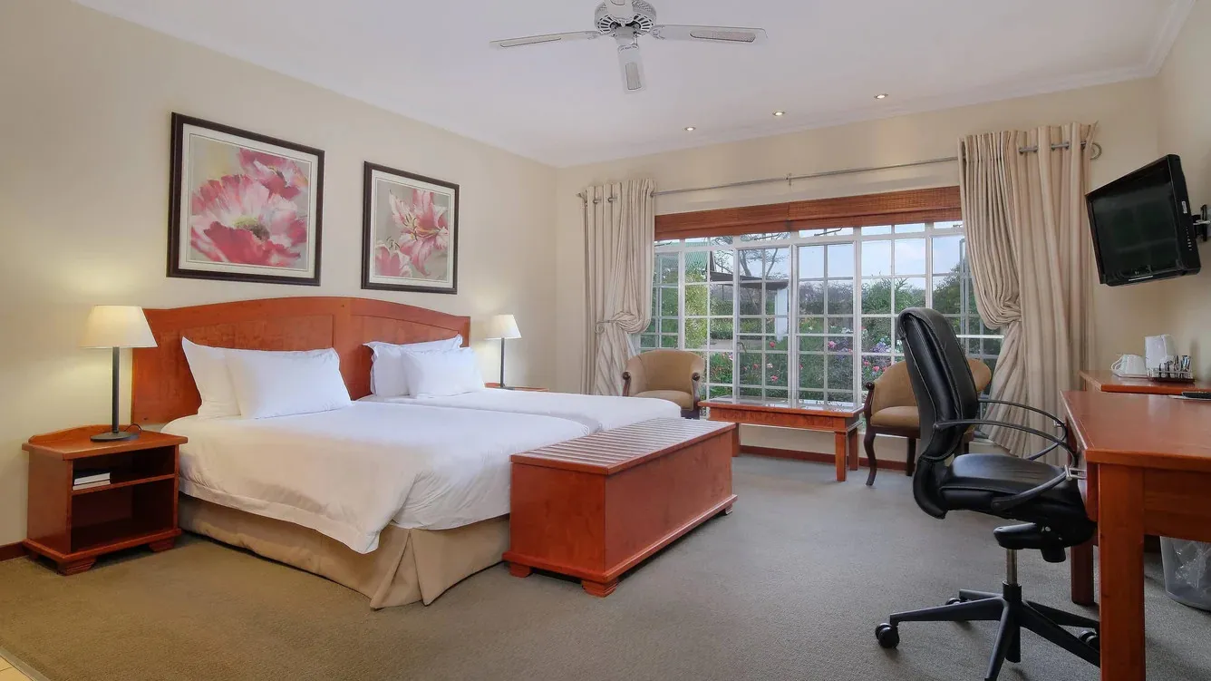 Hotel room with a large bed desk chair and large windows with curtains