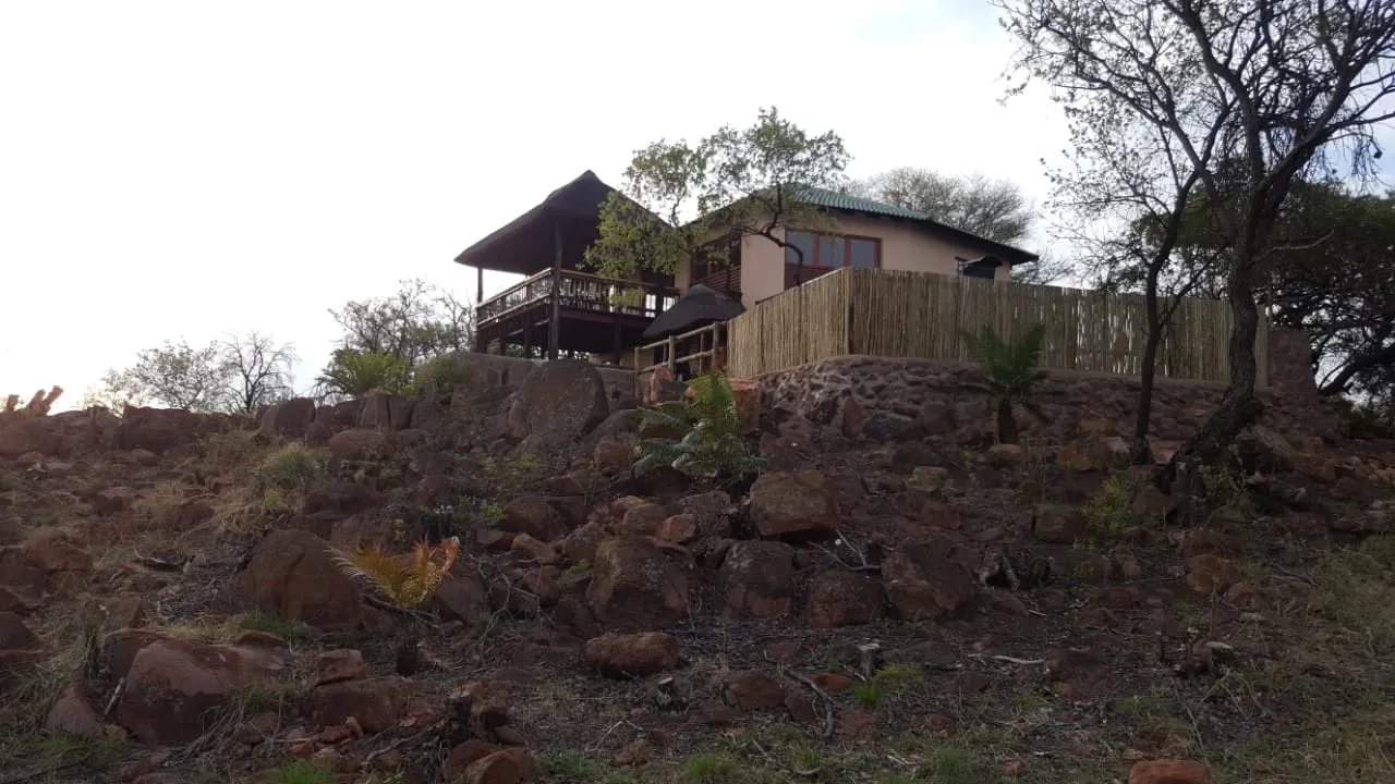 House on rocky hill with trees and shrubs in natural setting