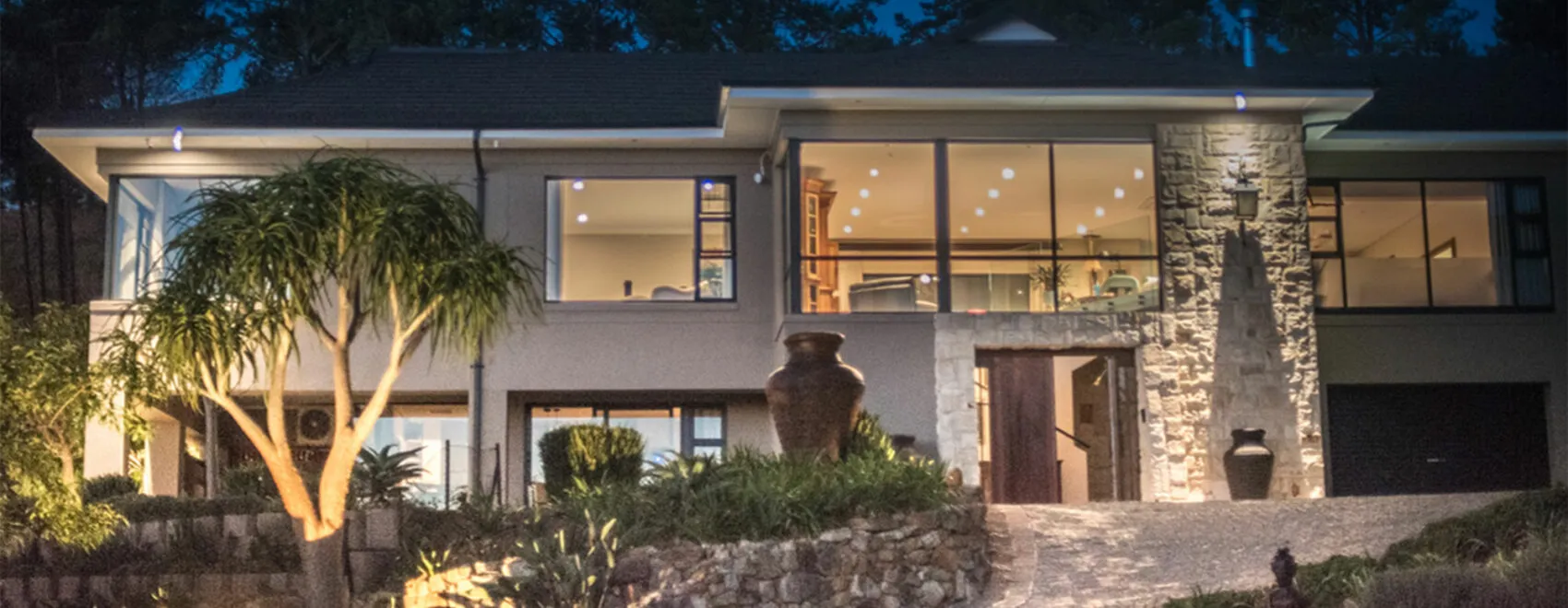 Modern house with large windows and stone entrance lit up at night