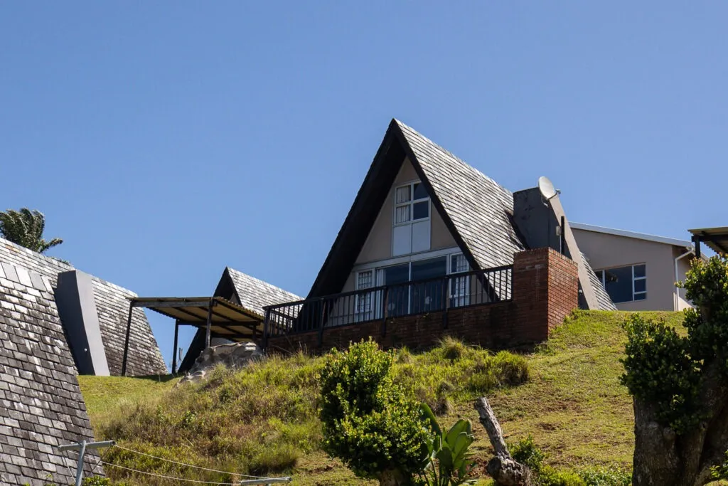 Aframe house on a grassy hill under a clear blue sky