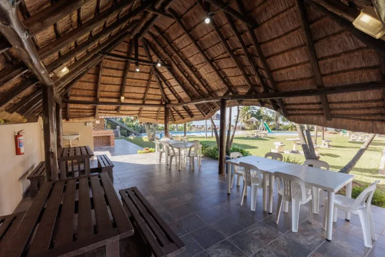 Wooden shelter with tables and chairs overlooking a grassy area