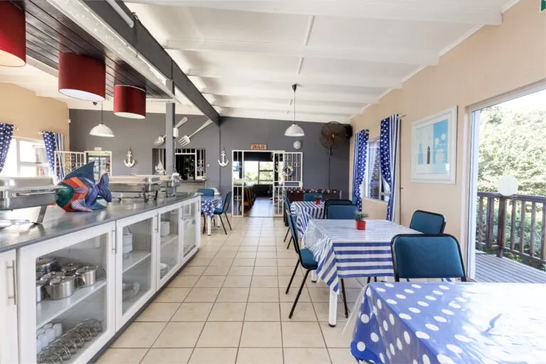 Dining area with blue and white tablecloths chairs and a serving counter