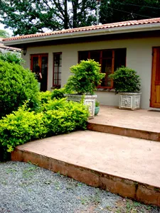 House with potted plants on steps and gravel driveway in front