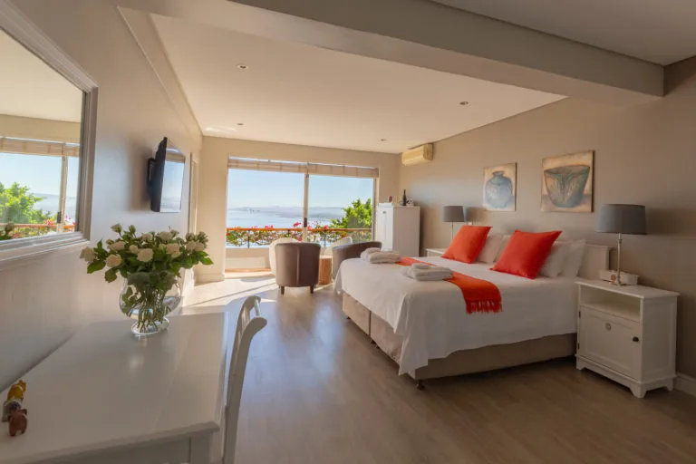 Bright bedroom with large window ocean view and orange and white decor