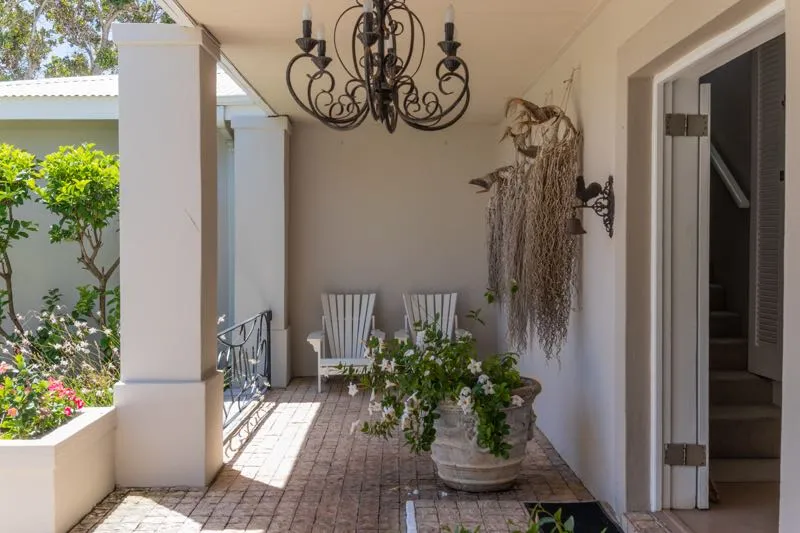 Covered patio with chairs potted plant and decorative wall hangings