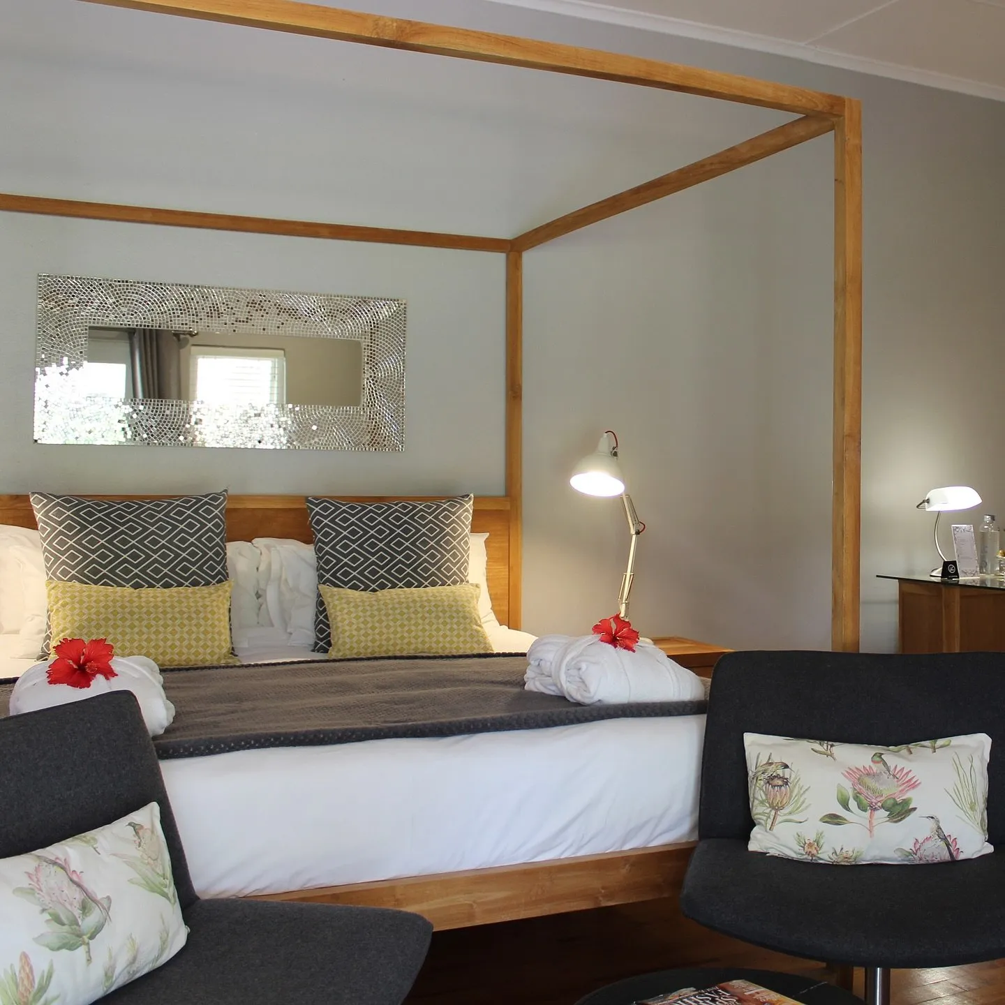 Wooden fourposter bed with pillows towels and a bedside lamp in a bedroom
