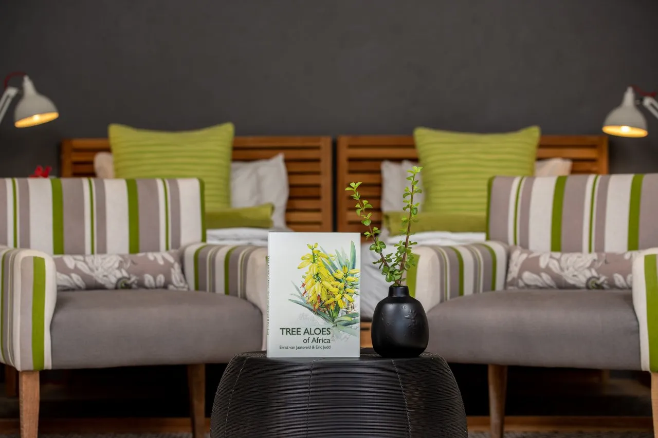 Book on a table in a modern living room with striped chairs and green cushions
