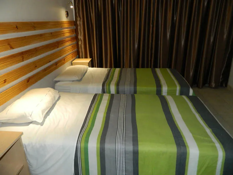 Two single beds with green and grey striped covers in a bedroom