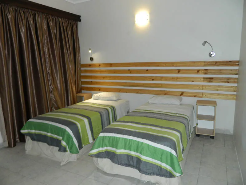 Two single beds with striped bedding in a bedroom with wooden headboards