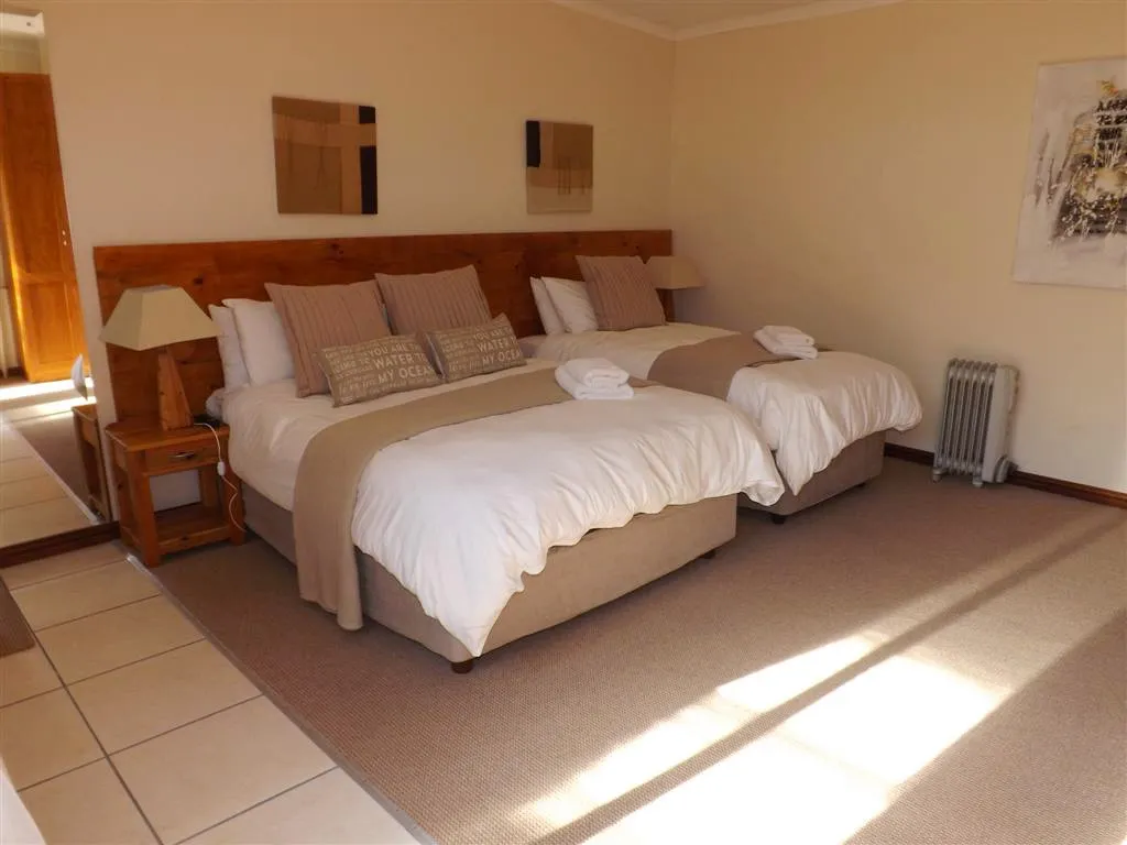 Two beds in a cozy bedroom with wooden headboard and wall art