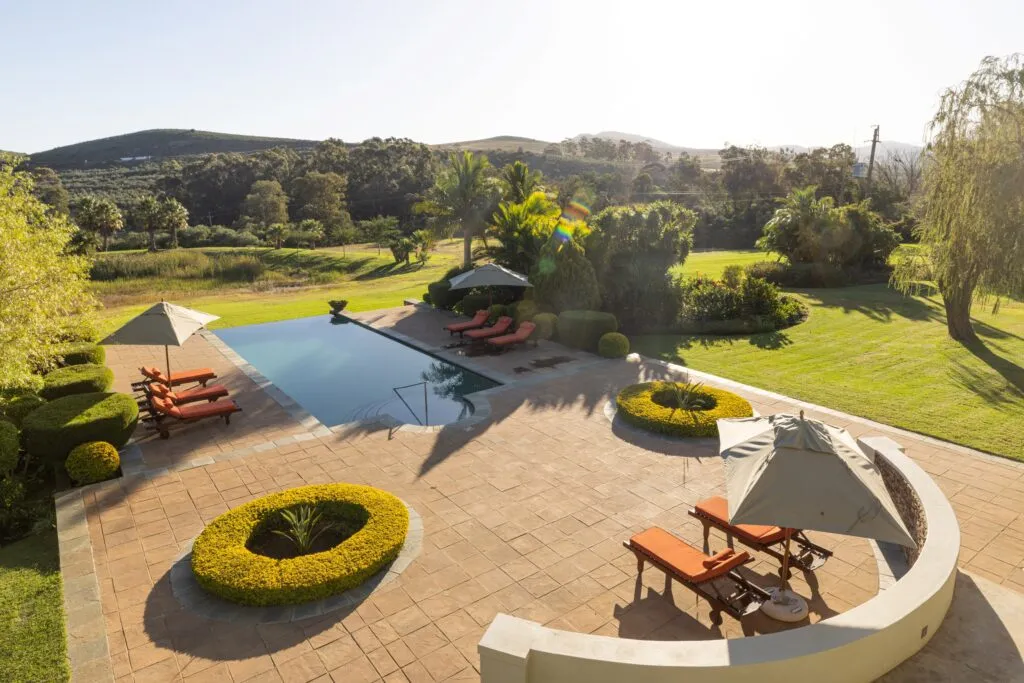 Swimming pool with lounge chairs and umbrellas in a landscaped garden setting
