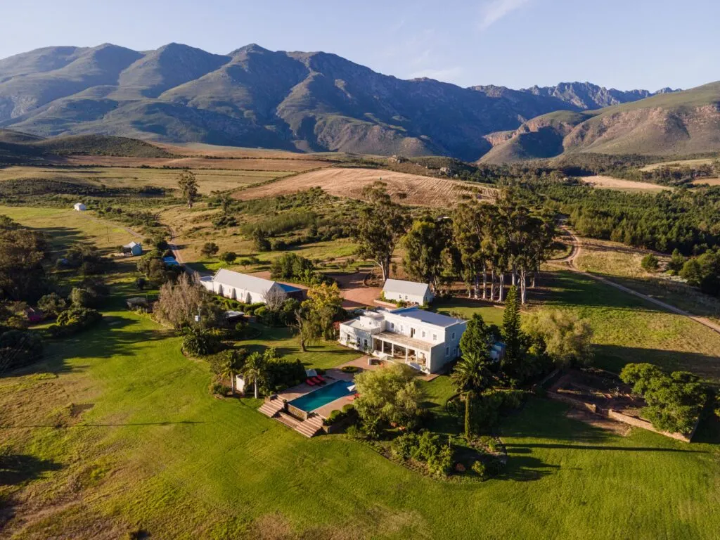 Country house with pool surrounded by green fields and mountains in the background