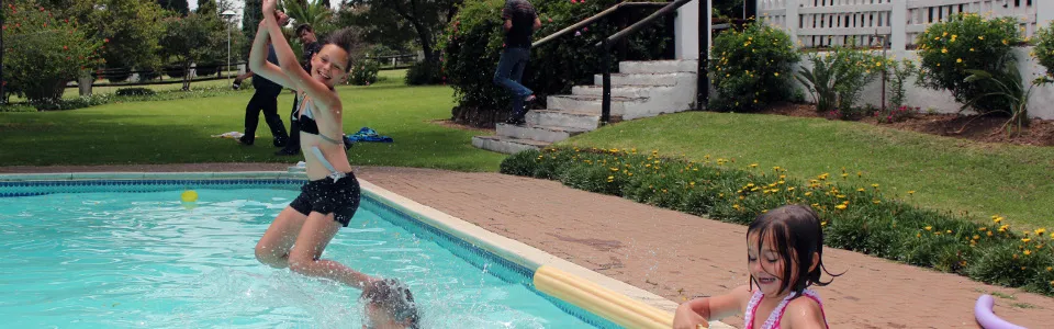 A child jumps into a swimming pool while another child watches