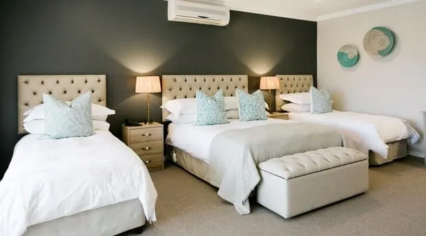 Three beds in a bedroom with neutral decor and wall art