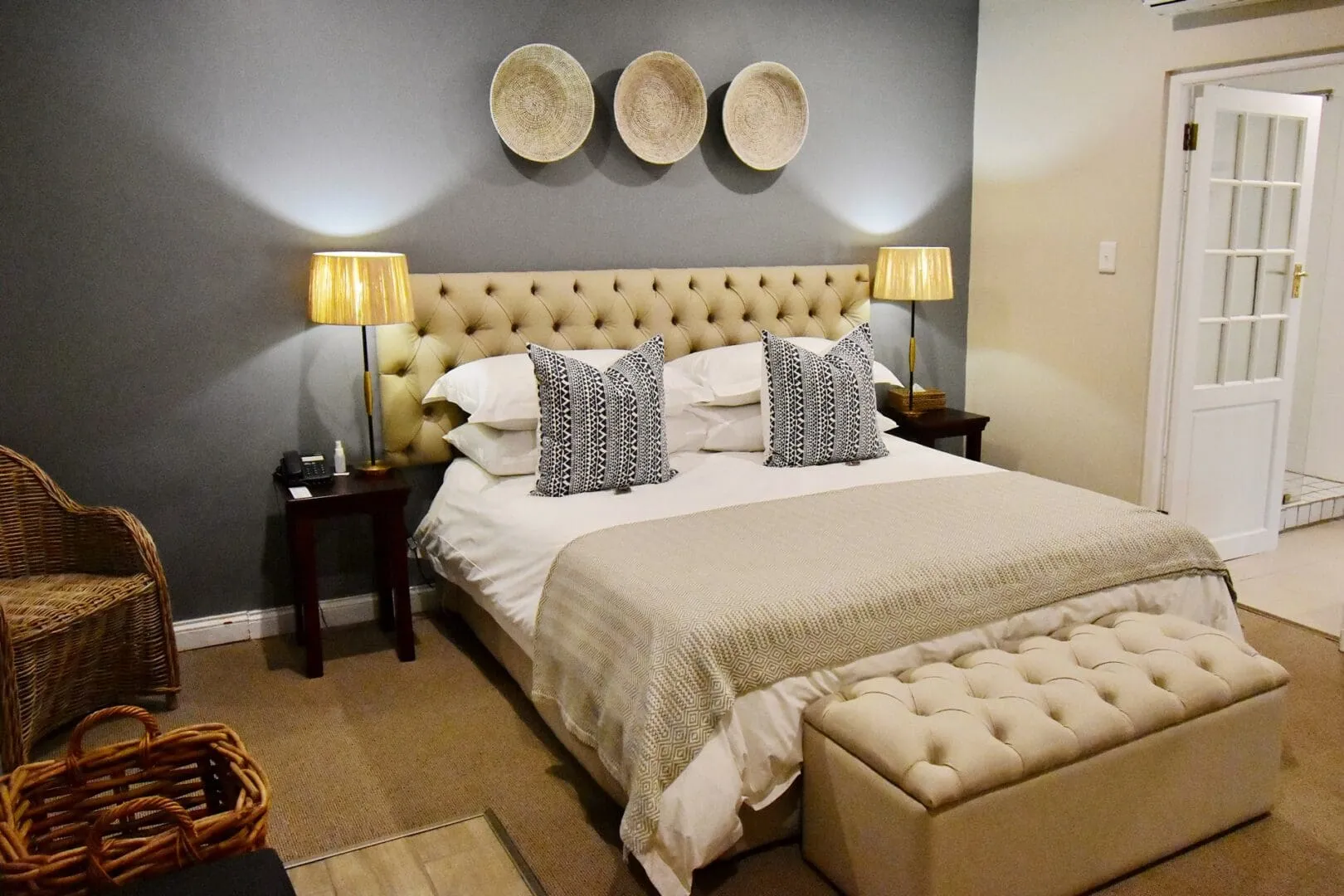 Cozy bedroom with a large bed bedside lamps and a tufted ottoman