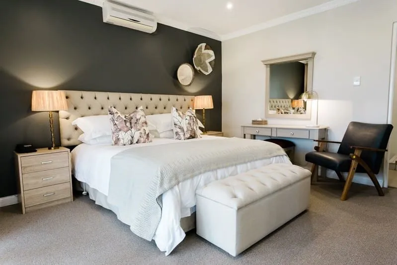 Modern bedroom with large bed bedside tables and a vanity with a chair