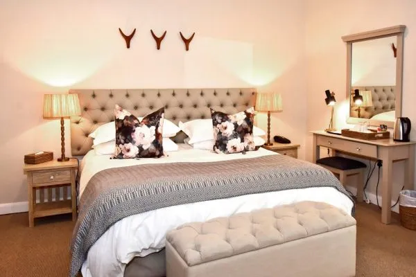 Cozy bedroom with large bed floral pillows and bedside tables with lamps