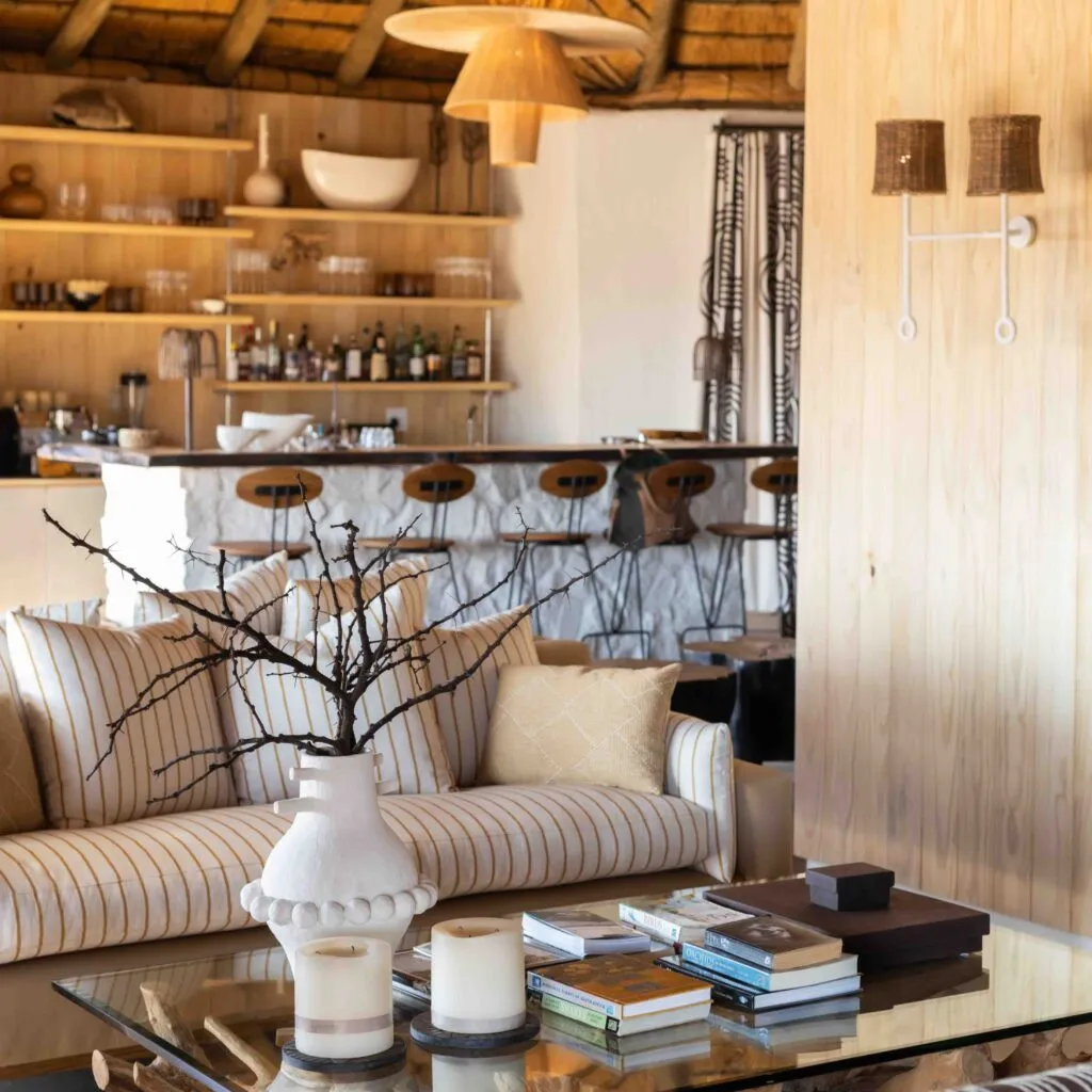 Modern living room with striped sofa decorative vase and books on a glass table