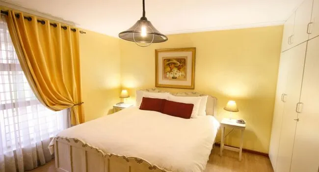 Bright bedroom with a large bed yellow walls and wooden wardrobes