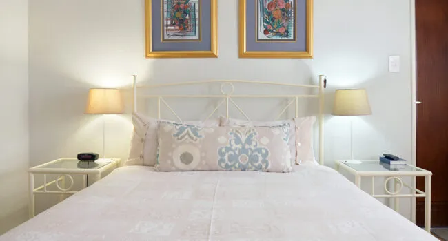 A neatly made bed with two pillows two bedside tables and two lamps