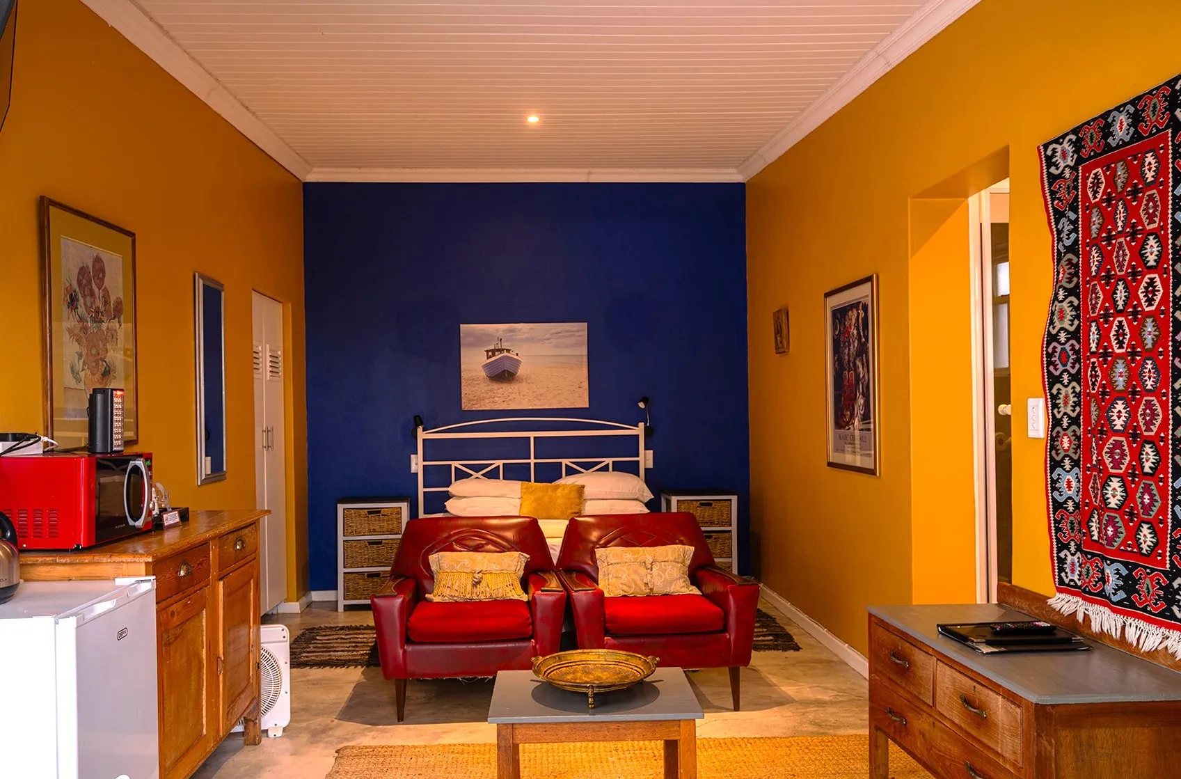 Bedroom with red armchairs blue and yellow walls and colorful decor