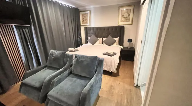 Bedroom with a bed two armchairs and artwork on the wall