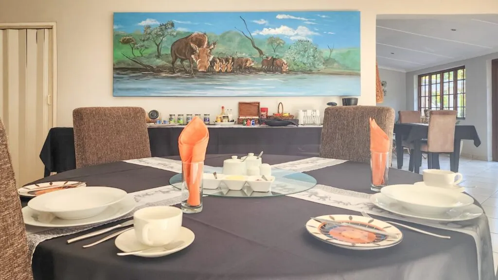 Dining table set with plates cups and napkins with a wildlife painting on the wall