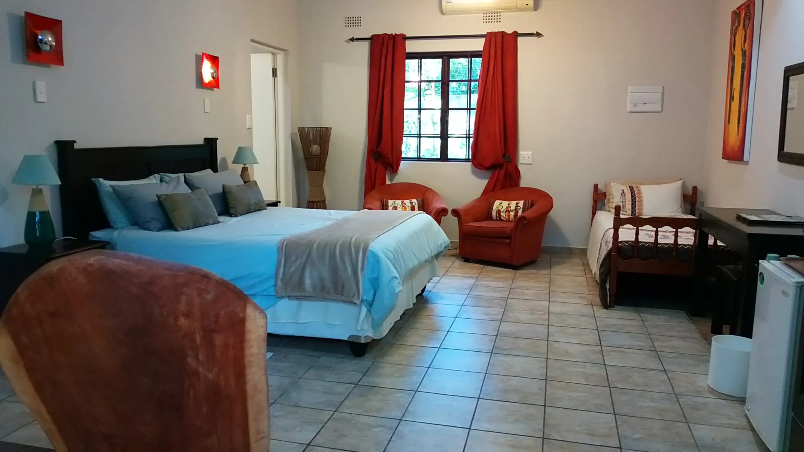 Bedroom with a bed two armchairs a crib and tiled floor