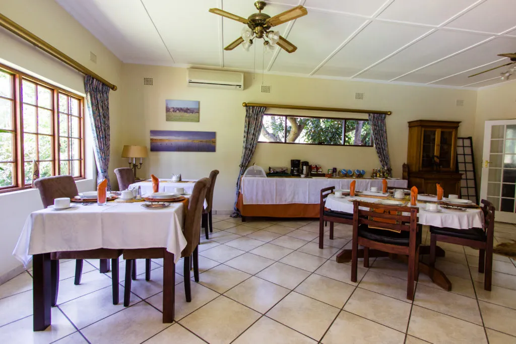 Dining area with tables chairs and a buffet setup in a bright room