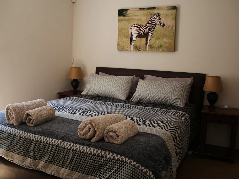 Bedroom with a large bed zebra painting and bedside tables with lamps