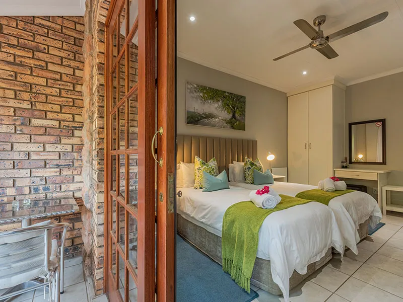 Bedroom with two beds green throws and towels viewed from a doorway