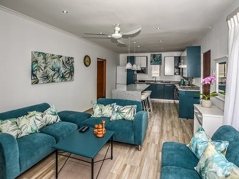 Modern living room with teal furniture open kitchen and tropical decor