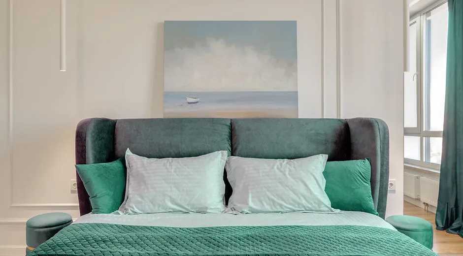 Modern bedroom with green bed pillows and painting above the headboard