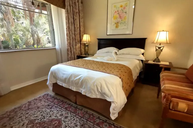 Cozy bedroom with a double bed two bedside lamps and a striped armchair