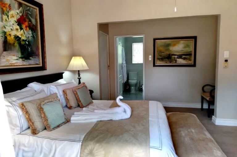 Bedroom with large bed floral painting and ensuite bathroom visible