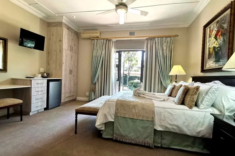 Cozy bedroom with large bed TV and garden view through glass doors