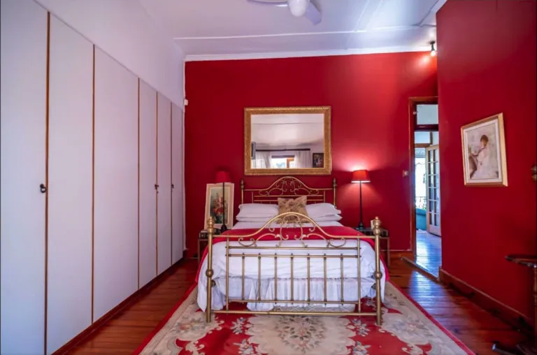 Red bedroom with white wardrobe brass bed and floral rug
