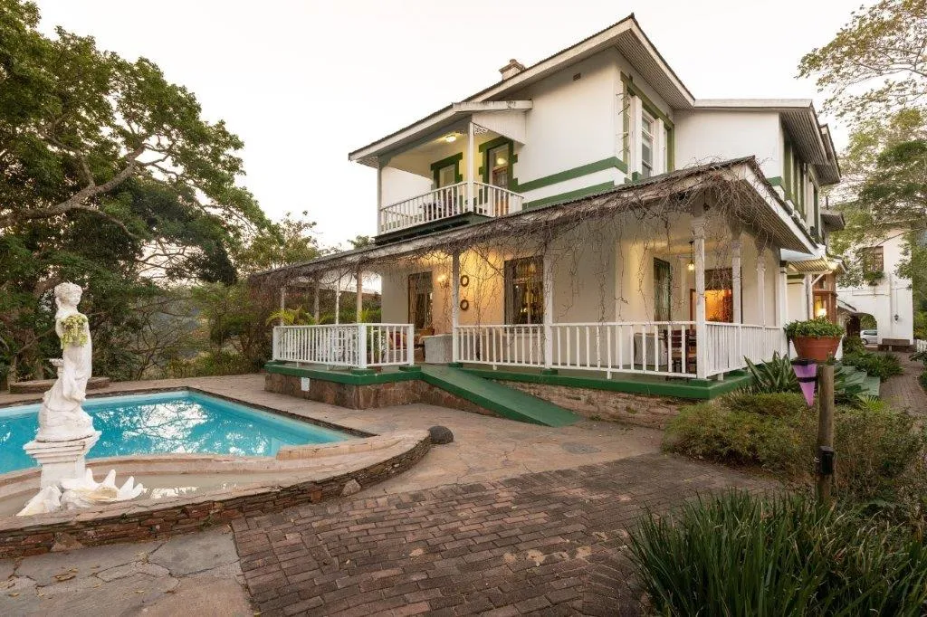 White house with green trim pool and garden in a tropical setting