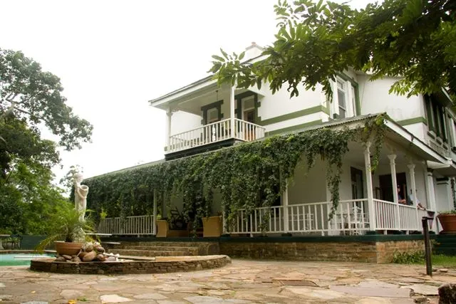 White house with green vines stone patio and garden statue in foreground