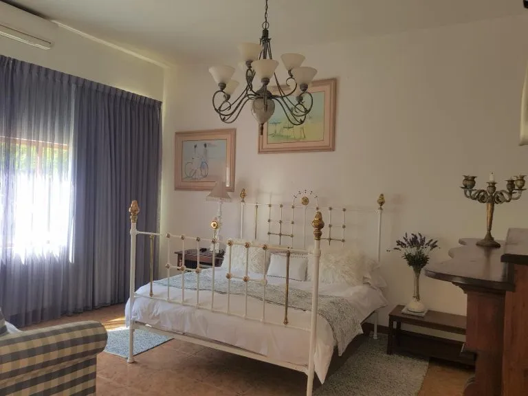 White metal bed with pillows in a cozy bedroom with blue curtains