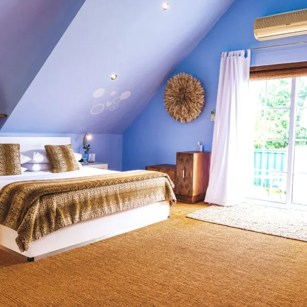 Bedroom with a large bed blue walls and an open window with curtains