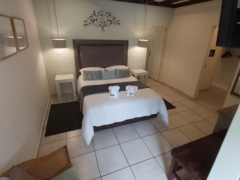A neatly made bed in a tidy minimalist bedroom with tiled floor