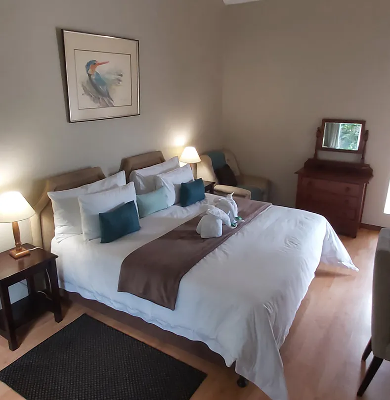 Cozy bedroom with a large bed bedside tables and a dresser with a mirror