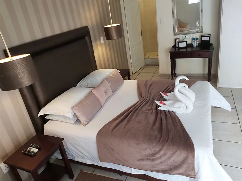 Bedroom with a neatly made bed two swan towels and bedside tables