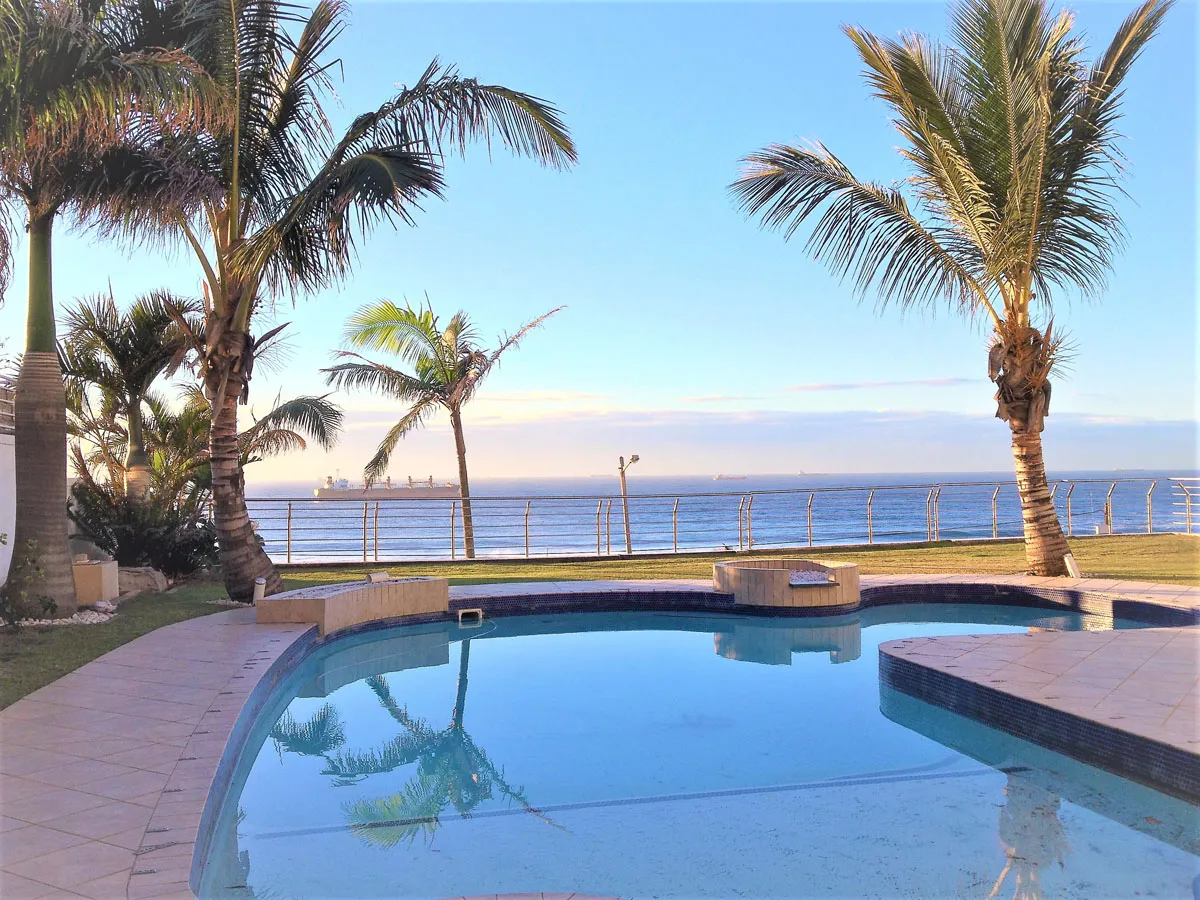 Swimming pool with palm trees overlooking the ocean on a sunny day