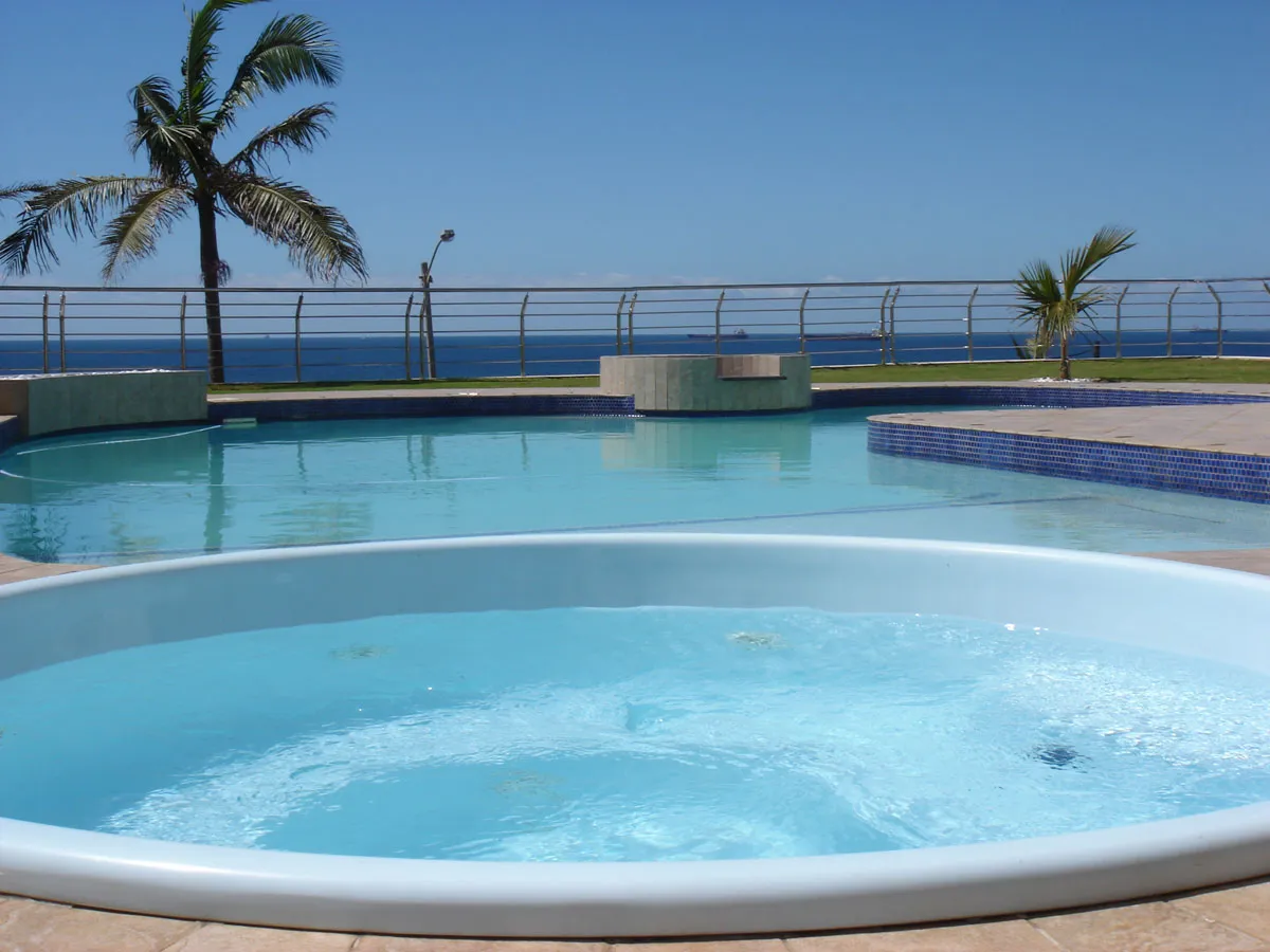 A hot tub and swimming pool with palm trees and ocean view