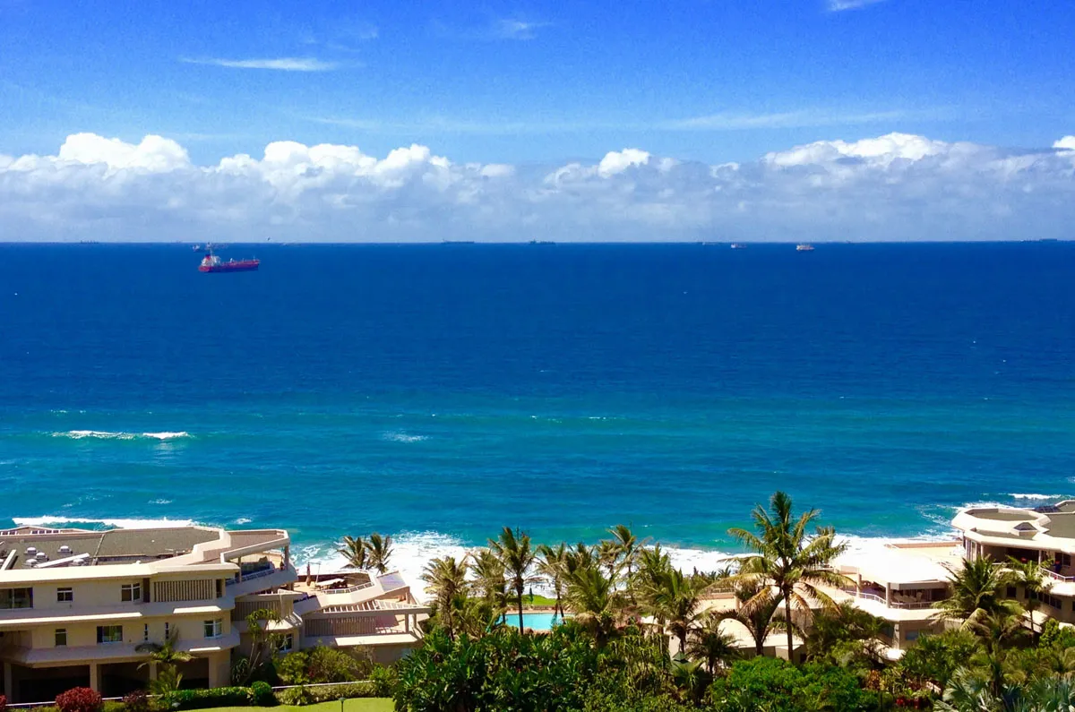 Ocean view with ships beach palm trees and buildings in the foreground