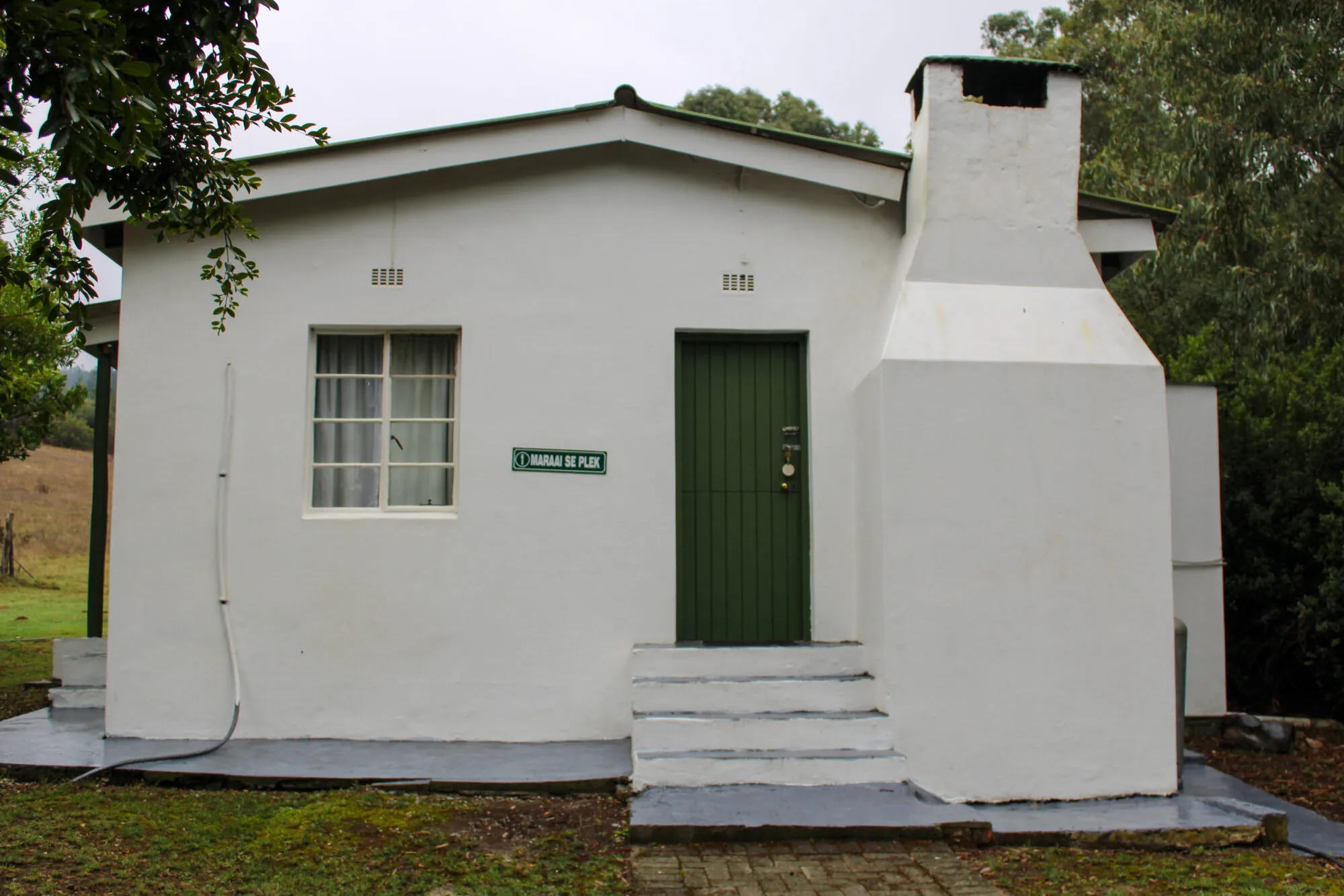Small white cottage with green door and window sign reading Casa da Far